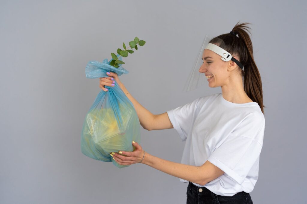 woman in white crew neck t shirt holding green plastic bag