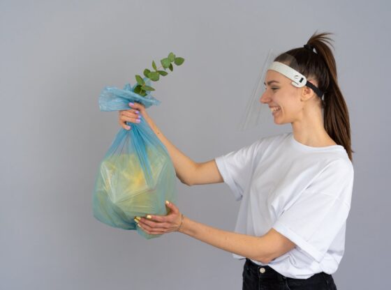 woman in white crew neck t shirt holding green plastic bag